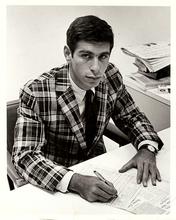 A young Mark Stolorow in a plaid jacket sitting at a desk