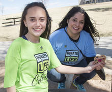 2018 Baldrige Award Recipient Donor Alliance photo showing two female volunteers outside holding a heart with Donate Life shirts.