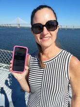 Baldrige Examiner Christy Hunter standing with ocean behind her, holding smart phone screen to camera