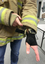 This image shows a glove being incorporated into a firefighter's jacket