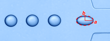 A series of drops of one liquid flowing in another through a microchannel, extending when they accelerate through a constriction