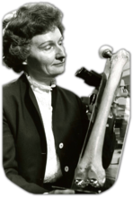 Photo of Dr. Anna C. Fraker with a laboratory sample metal hip replacement prosthesis.