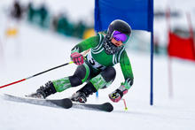 Person in green skiing outfit downhill skiing