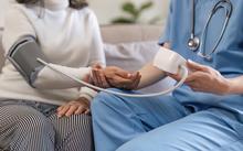 Photograph with health care professional taking a woman’s blood-pressure.