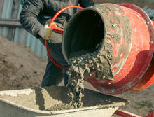 Photograph of a cement mixer pouring concrete into a wheelbarrow 