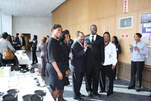 A group of people greet each other at a reception outside an auditorium.