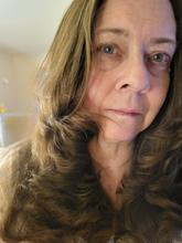 close up of woman with long hair curled on the ends to frame her face.