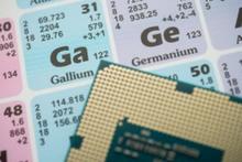 Close up view of the periodic table, focusing on Gallium (Ga) and Germanium (Ge). A semiconductor lies on the periodic table, indicating that Ga and Ge are critical minerals for semiconductor production.
