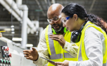 A man and woman work at a manufacturing dashboard.