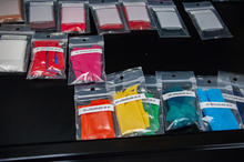 Different colored clothing samples are labeled and held inside plastic pouches inside a cabinet drawer in a lab.
