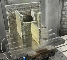 A nickel-based superalloy test specimen built using an additive manufacturing build process called ‘laser hot-wire directed energy deposition. The test specimen is sitting on a metal build plate attached to the build platform.