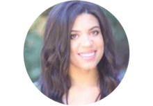 Close up of Kristin Nicholson, a woman with long brown hair, smiling for an outdoor headshot.