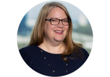 Professional headshot of Andrea Heithoff, a woman with long blonde hair and glasses, wearing a navy blouse and necklace, smiling.