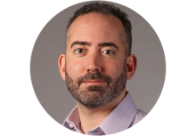 Professional headshot of Jered Floyd, a man with short salt and pepper colored hair, mustache, and beard, wearing a purple collared button up shirt.