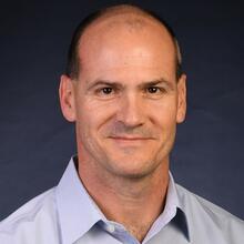 Professional headshot of Mark VanLandingham, a man with short black hair, in a blue collared shirt, smiling.