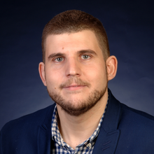 Antonio Montoro Bustos posing for a professional headshot against a dark blue studio backdrop.