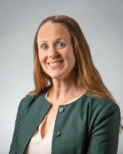Laura Pierce, a woman with long blonde hair, smiling for a professional headshot against a pale gray studio backdrop.