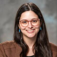 Fernanda Piorino, a woman with long dark brown hair, smiling for a professional headshot against a marbled gray studio background.