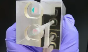 A NIST researcher holds a fixed length optical cavity (FLOC), a structure that enables highly accurate, quantum-based measurements of  pressure.
