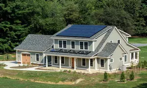 Photograph of large residential-style home with blue tile roof and solar panel in suburban campus setting.