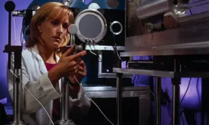 A woman in a lab coat adjusts a piece of scientific equipment