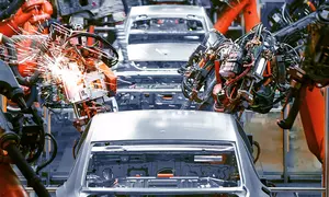 Cars on an assembly line with robotic arms doing work on them. Credit: Shutterstock/Jenson