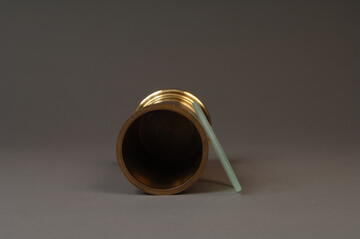 Brass volumetric standard, top view with glass cover laying at side
