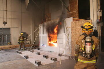 Firefighters outside a NIST test facility for examining  the impact of wind on fire spread