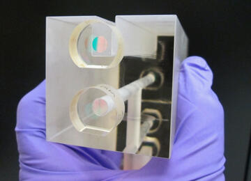 A NIST researcher holds a fixed length optical cavity (FLOC), a structure that enables highly accurate, quantum-based measurements of &nbsp;pressure.
