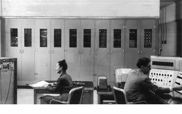 Lady on left and man on right at desks facing lab equipment