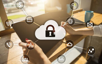 Woman sitting at table in front of window on an iPad with cyber security icons around.