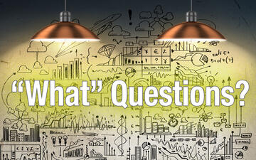 Overhead lights shining on the words "What" Questions with sketches on charts in the background
