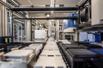 A robotic arm within the NIST Living Measurement Systems Foundry moves testing wells from one part of the system to another.
