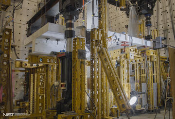 Horizontal concrete slab is visible in a forest of scaffolding and equipment in a large indoor space. 