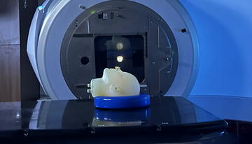 A model of a human head lies face up on the platform of an MRI machine. 