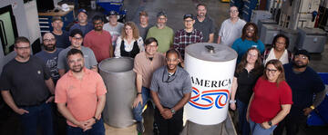 A group of people around a cylindrical time capsule