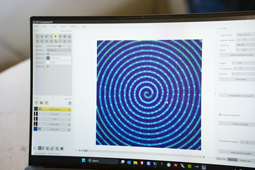 Laptop screen shows a tight, uniform spiral design. 