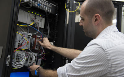 Timothy Zimmerman checking connections in the Cybersecurity for Smart Manufacturing Systems testbed