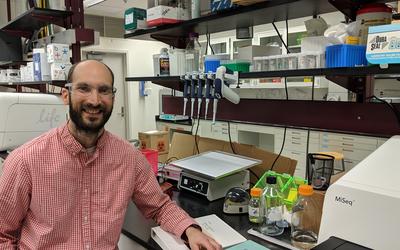 Justin Zook in a lab surrounded by genetic sequencing machines