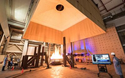 Photograph of large open room with fire engineers standing around a large fire test.