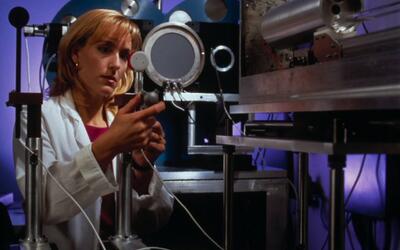 A woman in a lab coat adjusts a piece of scientific equipment
