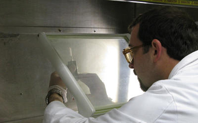 Denis Bergeron working behind an L-shield with a syringe containing a radiopharmaceutical.