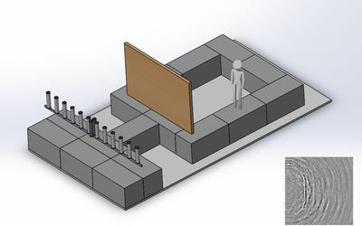 Human figure stands facing large wooden board. Behind that is a row of tubes sticking up from a base.