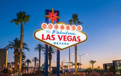 A neon sign that reads Welcome to Fabulous Las Vegas is lit up in neon in front of a sunset scene. 