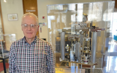 Antonio Possolo stands next to a museum display of a Kibble balance, a complex scientific device.