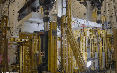 Horizontal concrete slab is visible in a forest of scaffolding and equipment in a large indoor space. 