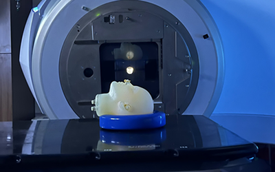 A model of a human head lies face up on the platform of an MRI machine. 