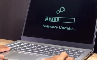 A laptop screen displays the words “software update” with a progress bar. 