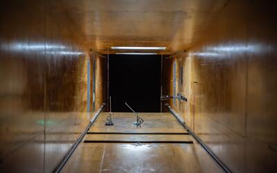 View from inside a square tunnel looking out into a dark space. Near the end of the tunnel, two small devices are attached to the floor. 