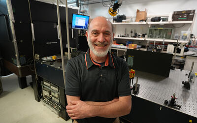 A man poses smiling in a laser laboratory.